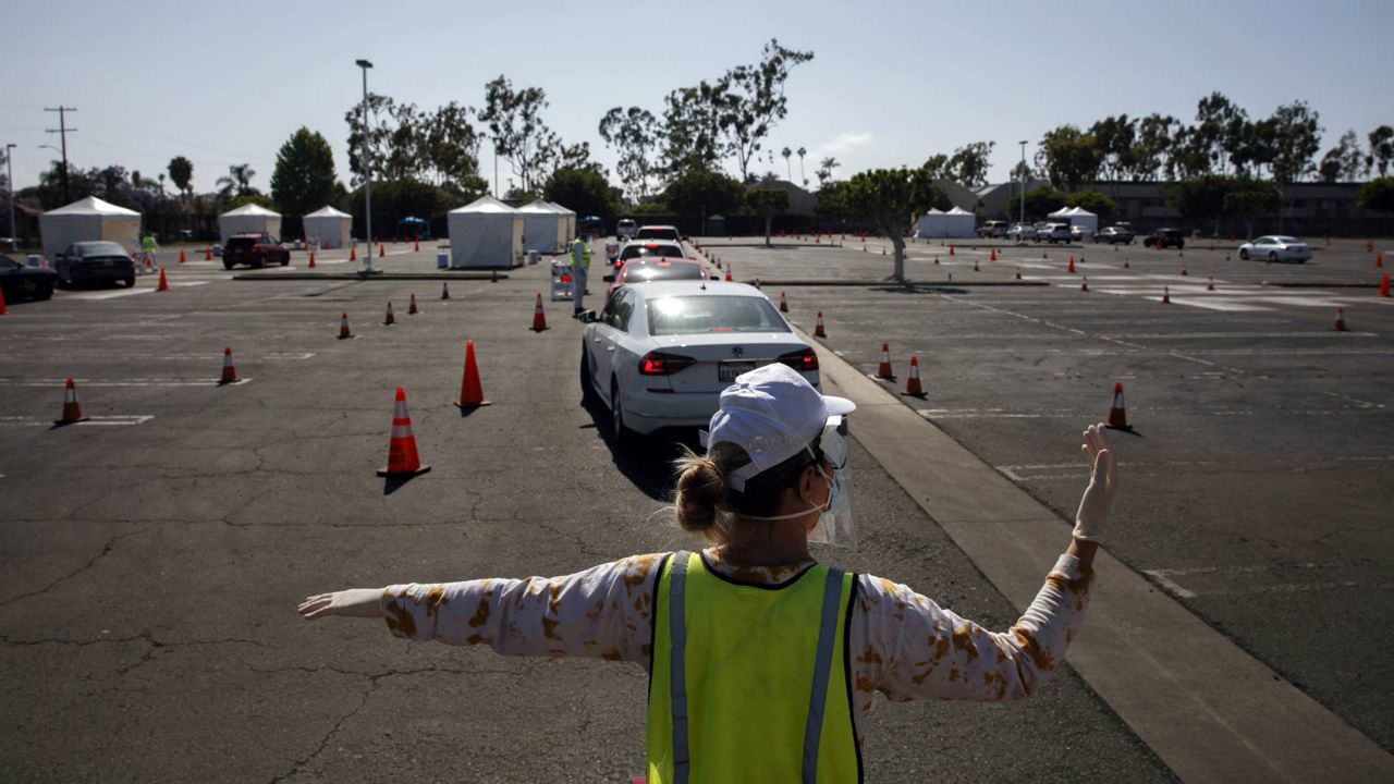 A volunteer controls traffic at a city-run, drive-thru COVID-19 testing site in South Central Los Angeles, May 22, 2020. (AP Photo/Jae C. Hong)