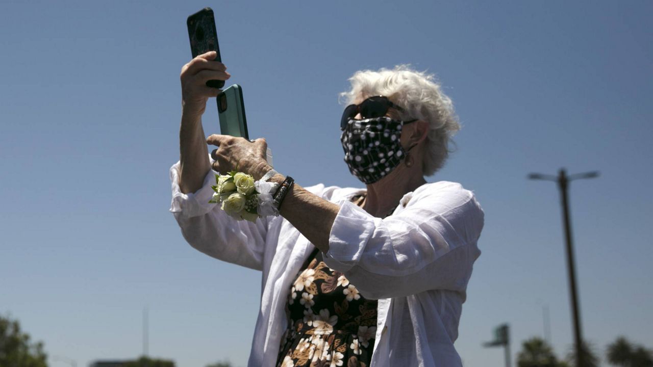 A woman records video during her daughter's marriage service in the parking lot of the Honda Center in Anaheim, Calif., May 26, 2020. (AP/Jae C. Hong)