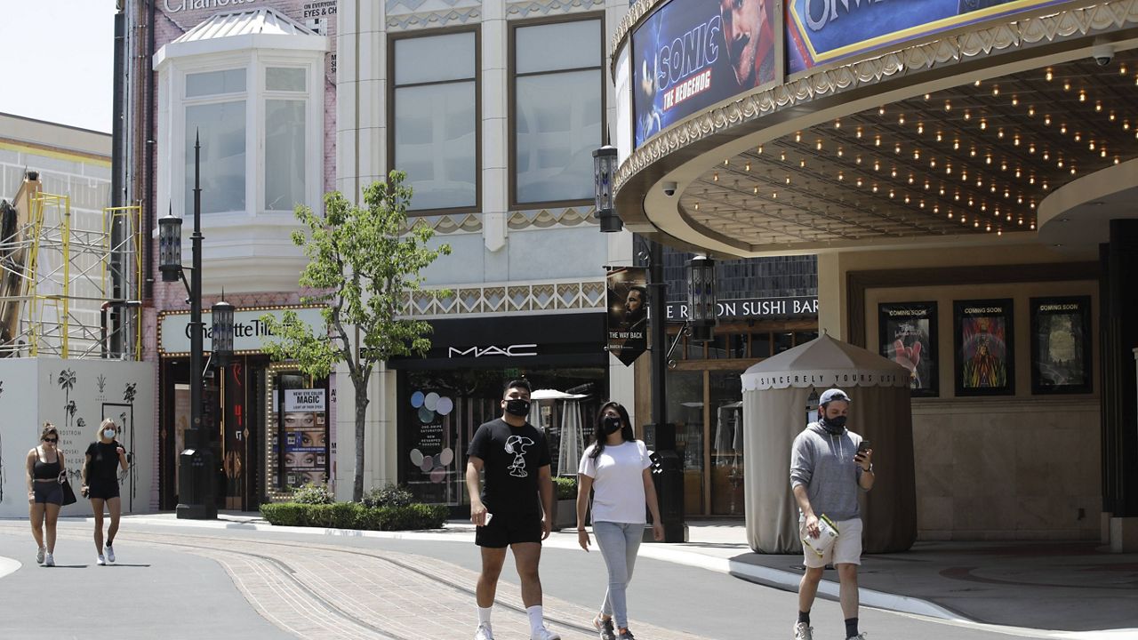 People walk in a mostly empty The Grove shopping center Wednesday, May 27, 2020, in Los Angeles. (AP Photo/Marcio Jose Sanchez)