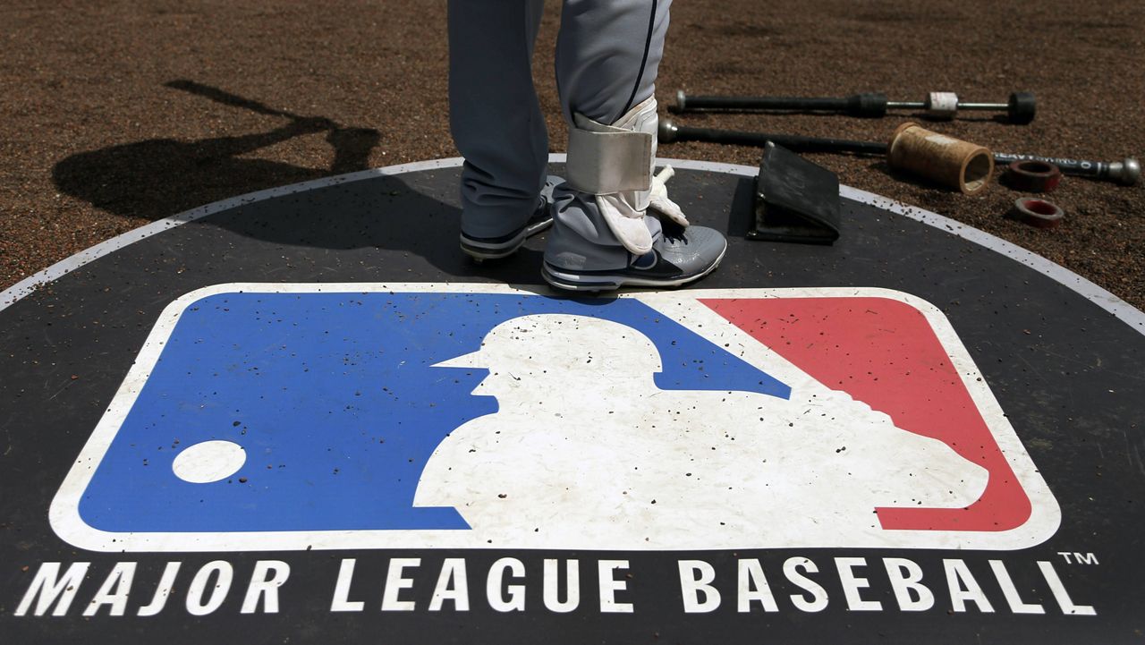 A player stands on the Major League Baseball logo in an on-deck circle. (AP Photo/Charles Rex Arbogast, File)