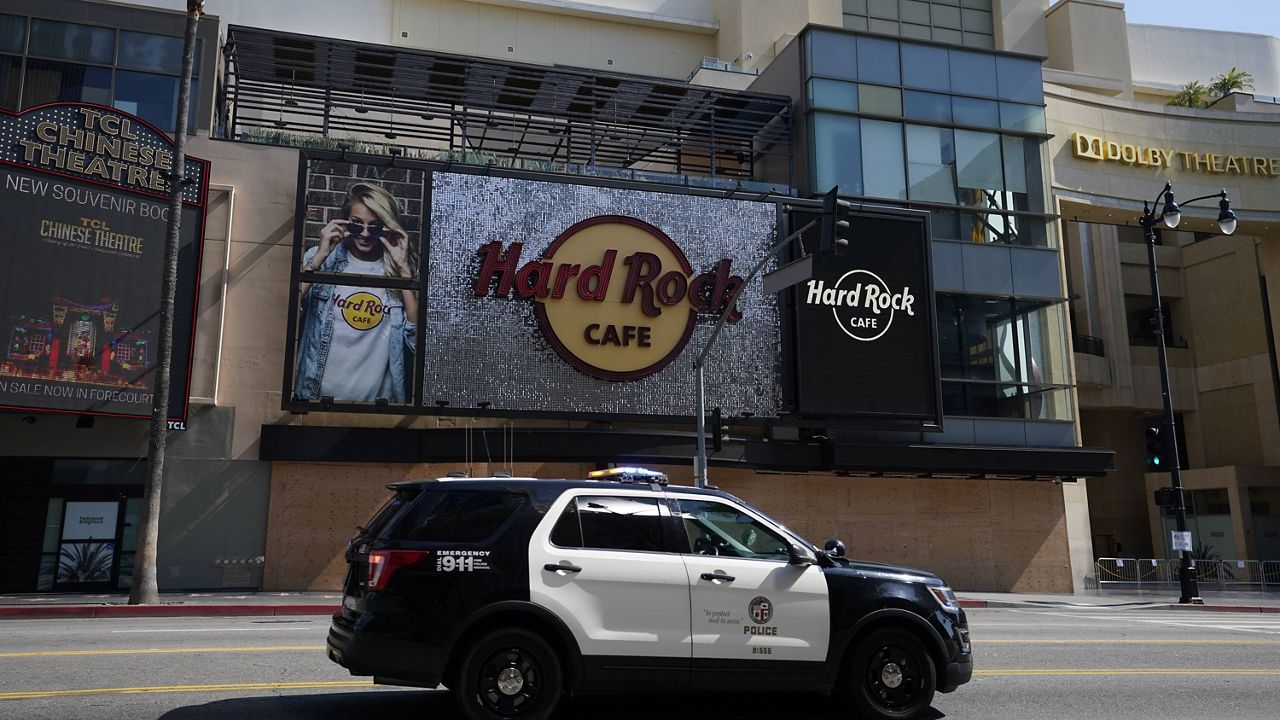 A police car drives past Hard Rock Cafe, Wednesday, June 3, 2020, in the Hollywood area of Los Angeles. (AP Photo/Ashley Landis)