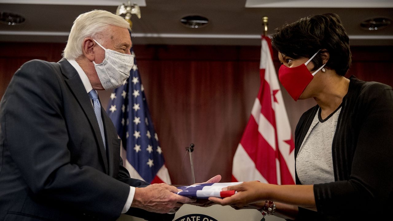 District of Columbia Mayor Muriel Bowser, right, presents House Majority Leader Steny Hoyer of Md., left, with a flag with 51 stars on it during a news conference on D.C. statehood on Capitol Hill, Tuesday, June 16, 2020, in Washington. Hoyer will hold a vote on D.C. statehood on July 26. (AP Photo/Andrew Harnik)