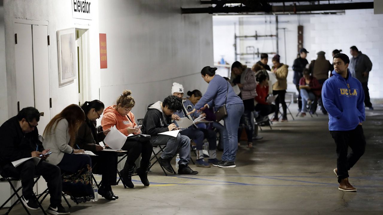 In this March 13, 2020 file photo, unionized hospitality workers wait in line in a basement garage to apply for unemployment benefits at the Hospitality Training Academy in Los Angeles. (AP Photo/Marcio Jose Sanchez, File)