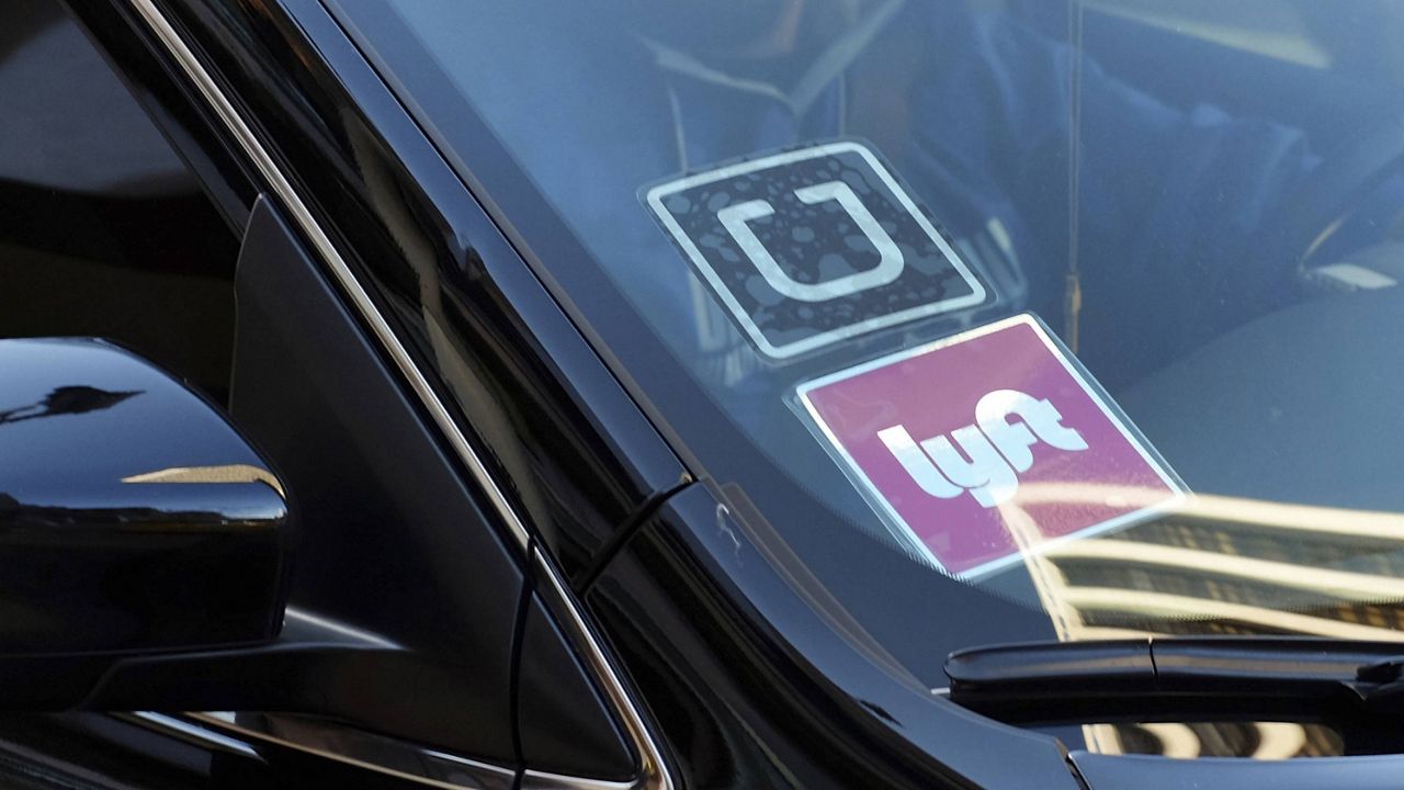In this Jan. 12, 2016, file photo, a ride-share car displays Lyft and Uber stickers on its front windshield in downtown Los Angeles. (AP Photo/Richard Vogel, File)