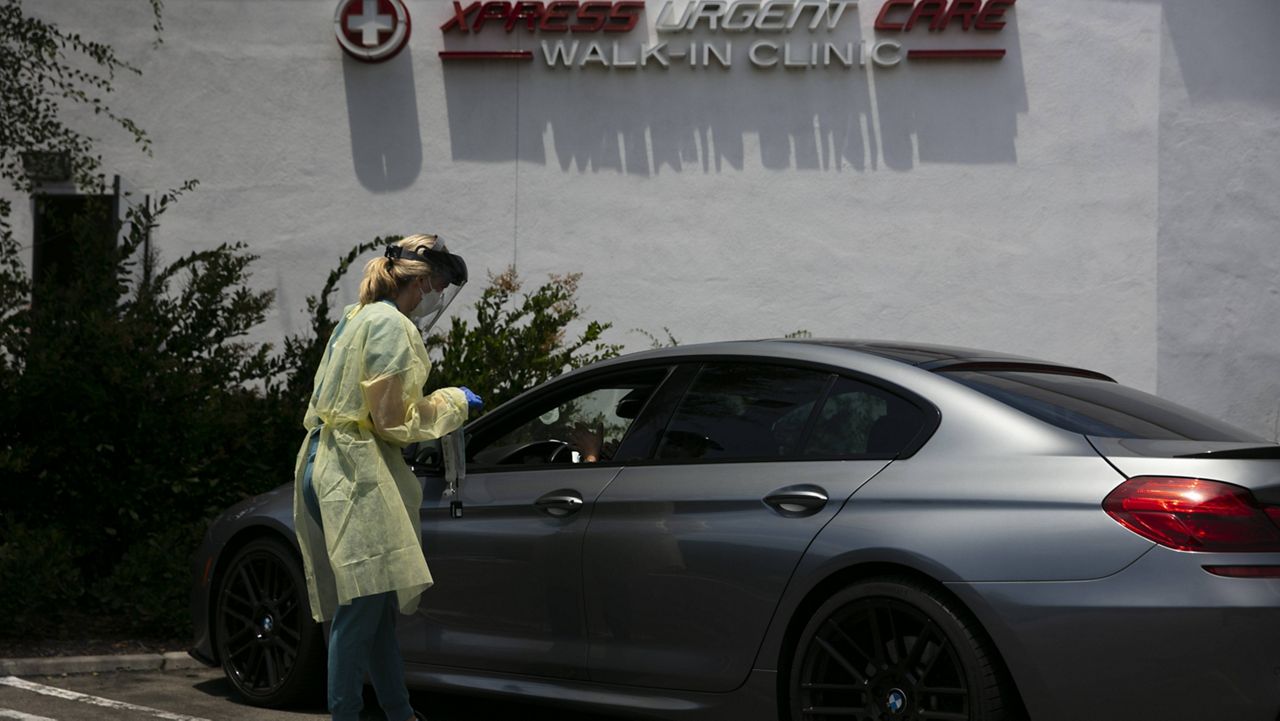 Physician assistant Nicole Kramer talks to a patient after collecting a nasal swab sample for COVID-19 testing at Xpress Urgent Care Thursday, June 25, 2020, in Tustin, Calif. (AP Photo/Jae C. Hong)