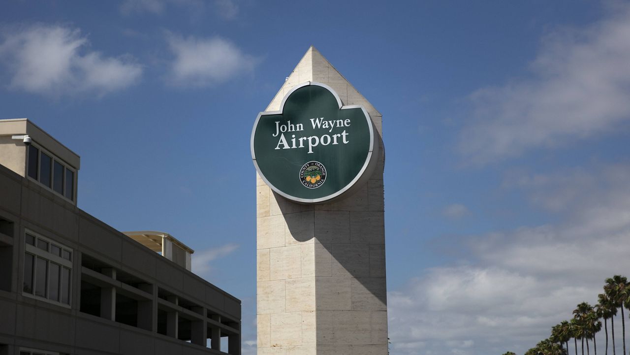 A John Wayne Airport sign stands next to a parking structure at John Wayne Airport in Santa Ana, Calif., Monday, June 29, 2020. (AP Photo/Jae C. Hong)