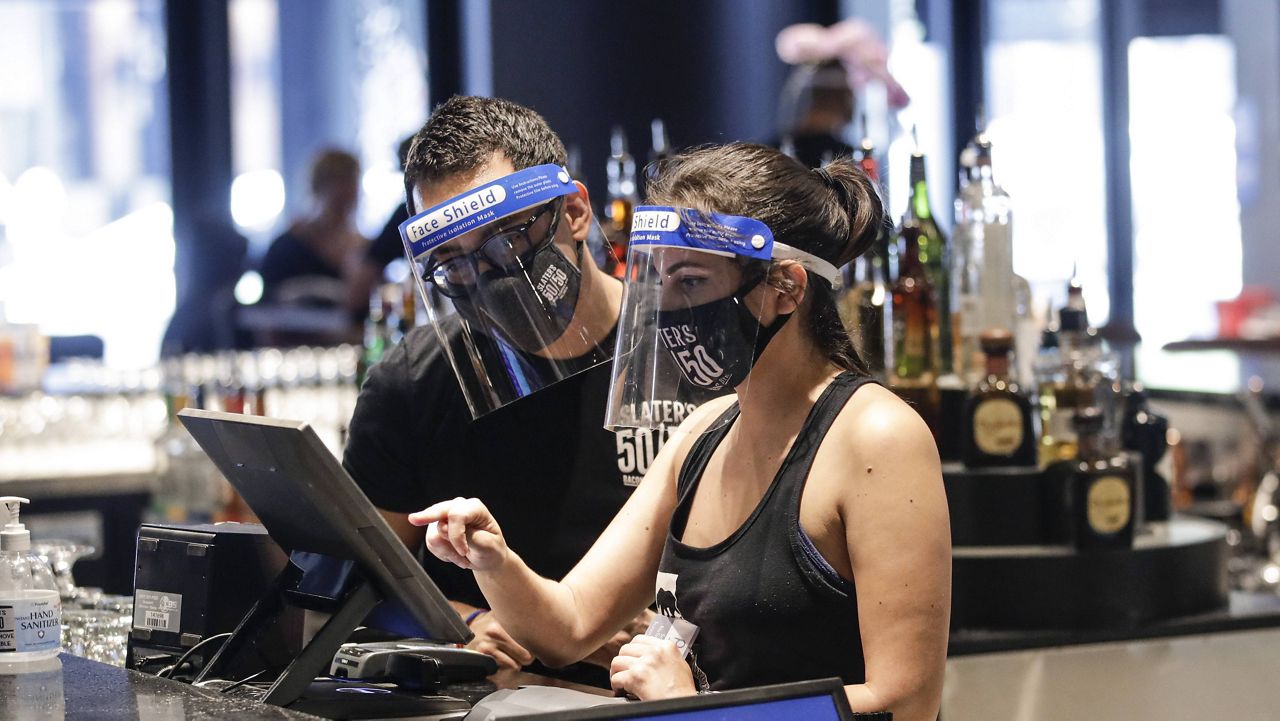 Bartenders were masks and face shields as they work at Slater's 50|50 in Wednesday, July 1, 2020, in Santa Clarita, Calif. (AP Photo/Marcio Jose Sanchez)
