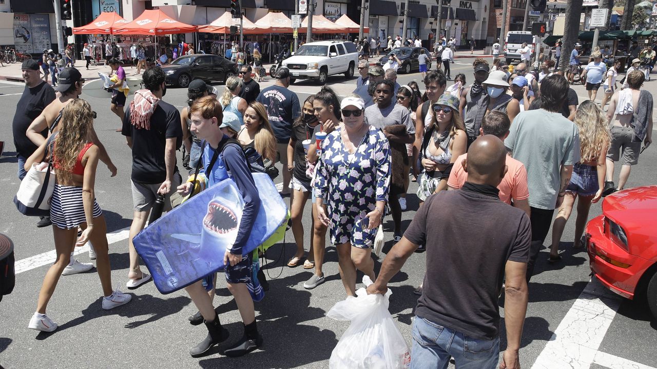 In this June 27, 2020, file photo, beach goers cross the Pacific Coast Highway in Huntington Beach, Calif. (AP Photo/Marcio Jose Sanchez, File)