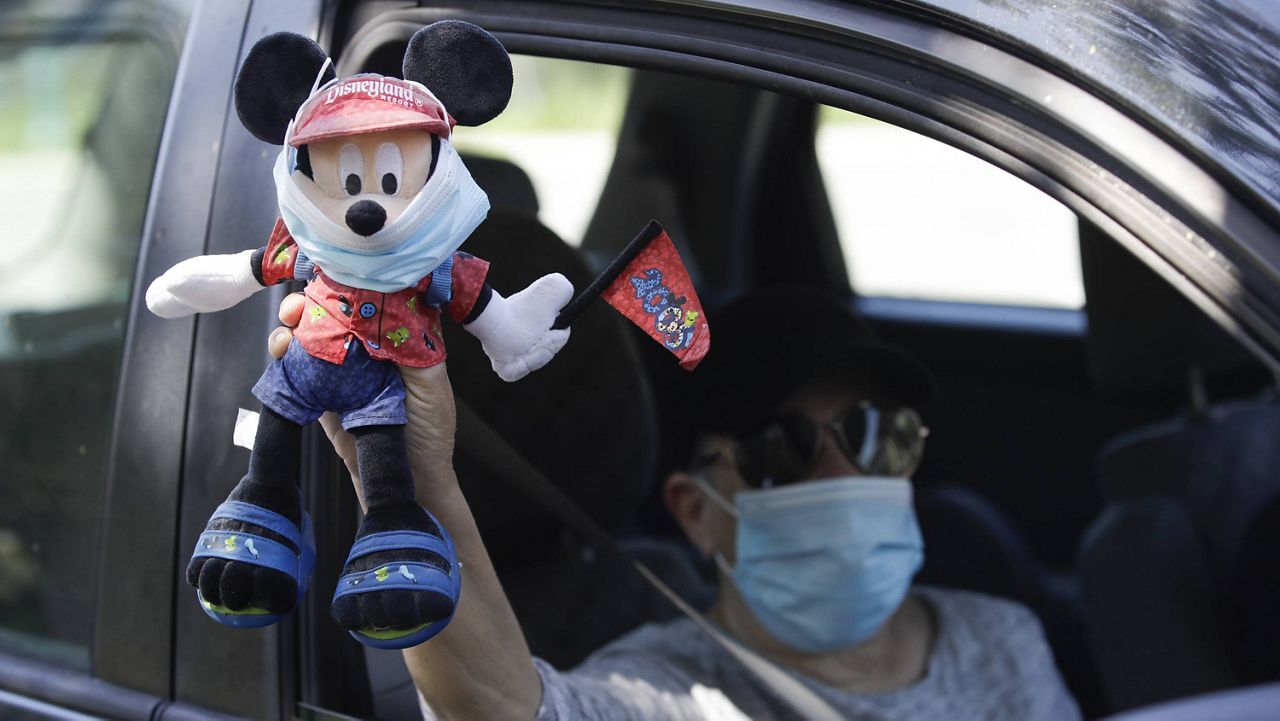 In this June 27, 2020 photo, a Disney employee carries a Mickey Mouse doll during a drive-by protest to demand a safe reopening amid the coronavirus pandemic in Anaheim, Calif. (AP/Marcio Jose Sanchez)