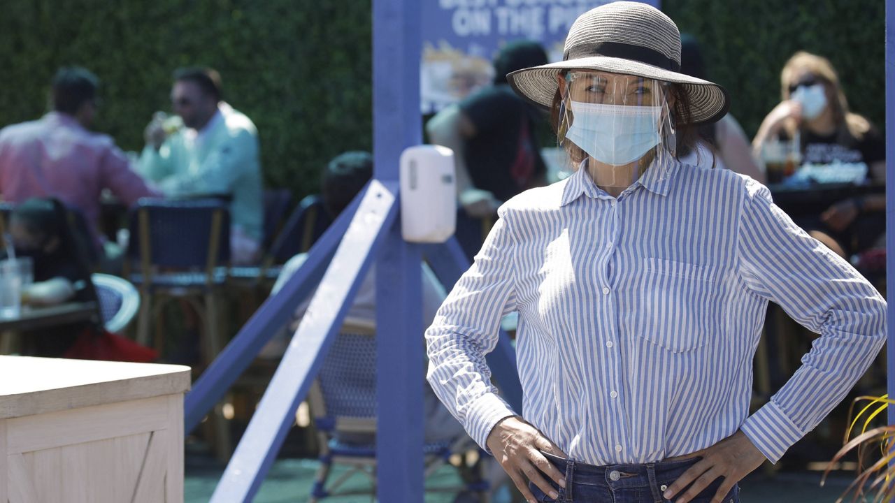 A hostess waits to sit customers on a restaurant at the pier Sunday, July 12, 2020, in Santa Monica, Calif., amid the coronavirus pandemic.