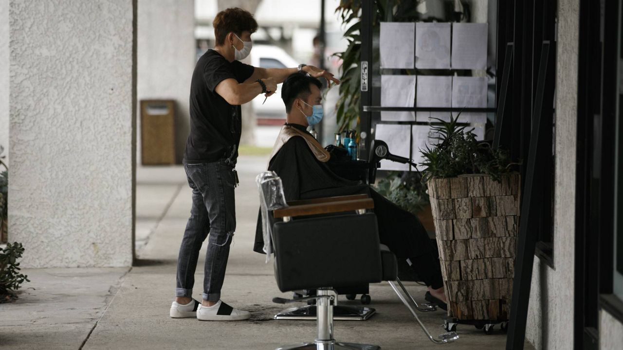 A hairstylist gives a haircut at his outdoor salon in Fountain Valley, Calif., July 22, 2020. (AP/Jae C. Hong)