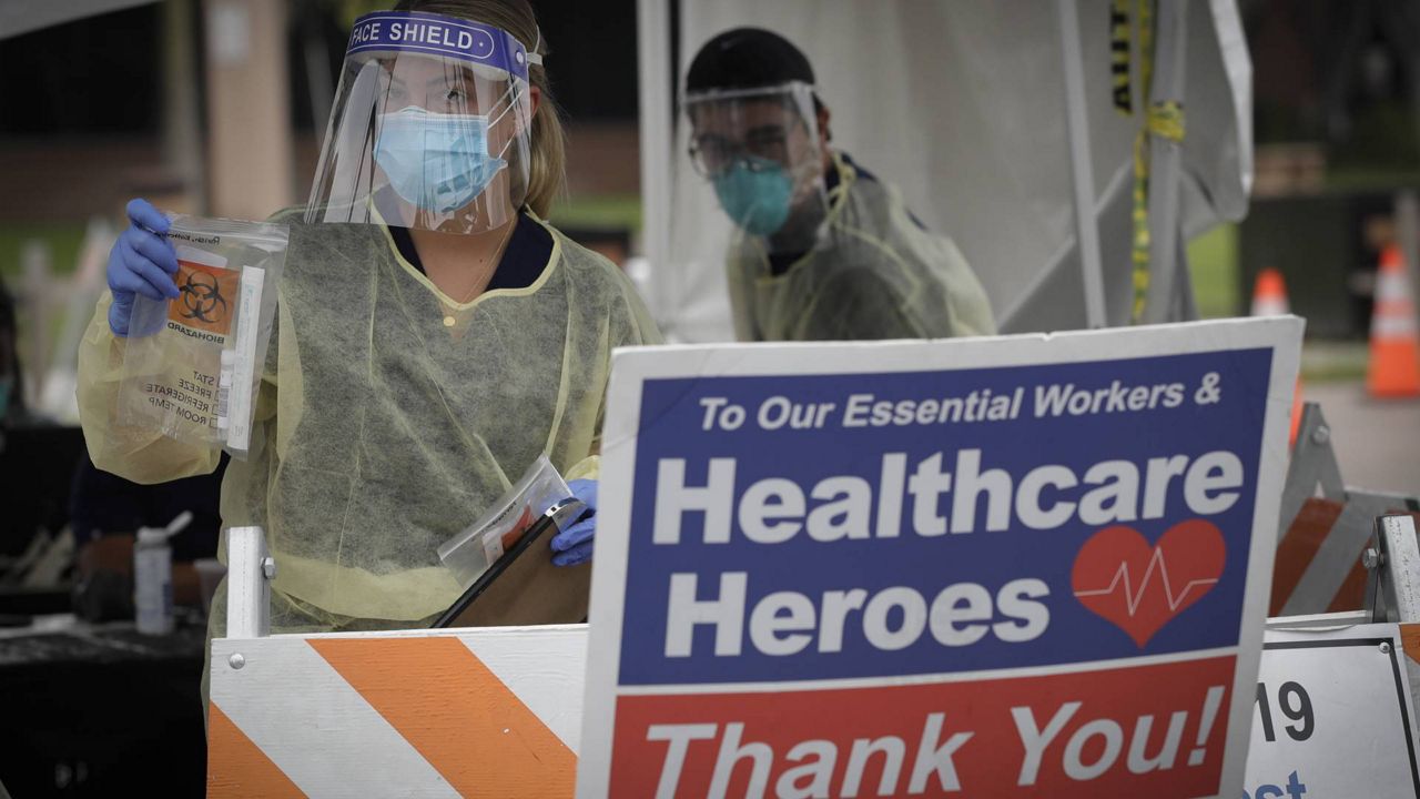 A worker hands out testing kits at a mobile Coronavirus testing site at the Charles Drew University of Medicine and Science, July 22, 2020, in Los Angeles. (AP Photo/Marcio Jose Sanchez)