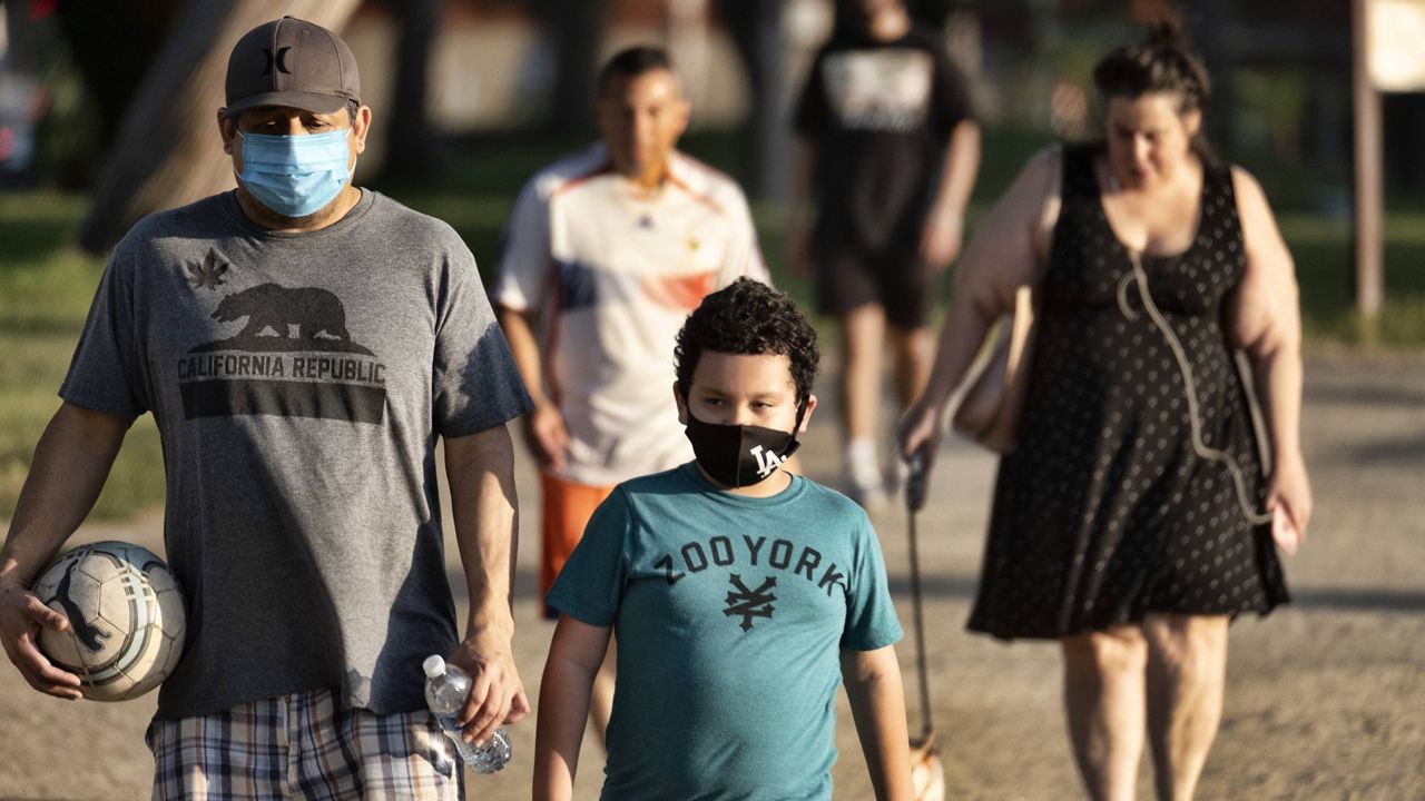 In this May 9, 2020, file photo, adults and children wearing masks amid the coronavirus pandemic exercise around a track at the Van Nuys/Sherman Oaks Recreation Center. (AP Photo/Richard Vogel, File)