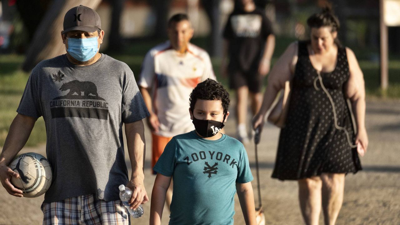 In this May 9, 2020 photo, adults and children wearing masks amid the pandemic exercise at the Van Nuys/Sherman Oaks Recreation Center in Los Angeles. (AP Photo/Richard Vogel)