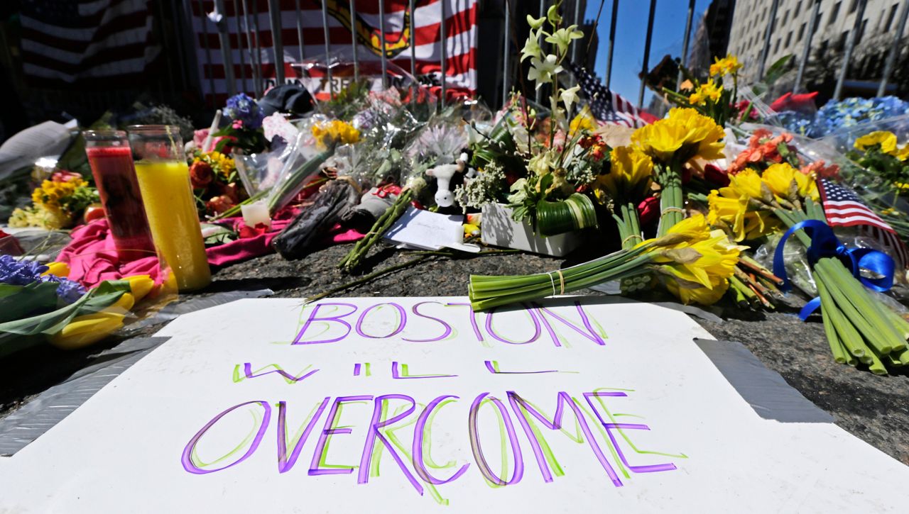 FILE - In this April 17, 2013 photograph, flowers and signs adorn a barrier, two days after two explosions killed three and injured hundreds, at Boylston Street near the of finish line of the Boston Marathon at a makeshift memorial for victims and survivors of the bombing. (AP Photo/Charles Krupa, File)