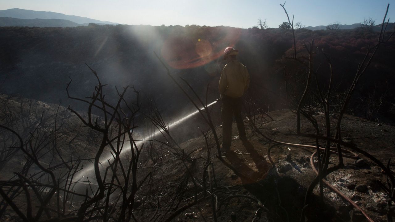 A member of hand crews works on the remaining hot spots at the Apple Fire in Cherry Valley, Calif., Saturday, Aug. 1, 2020. (AP Photo/Ringo H.W. Chiu)