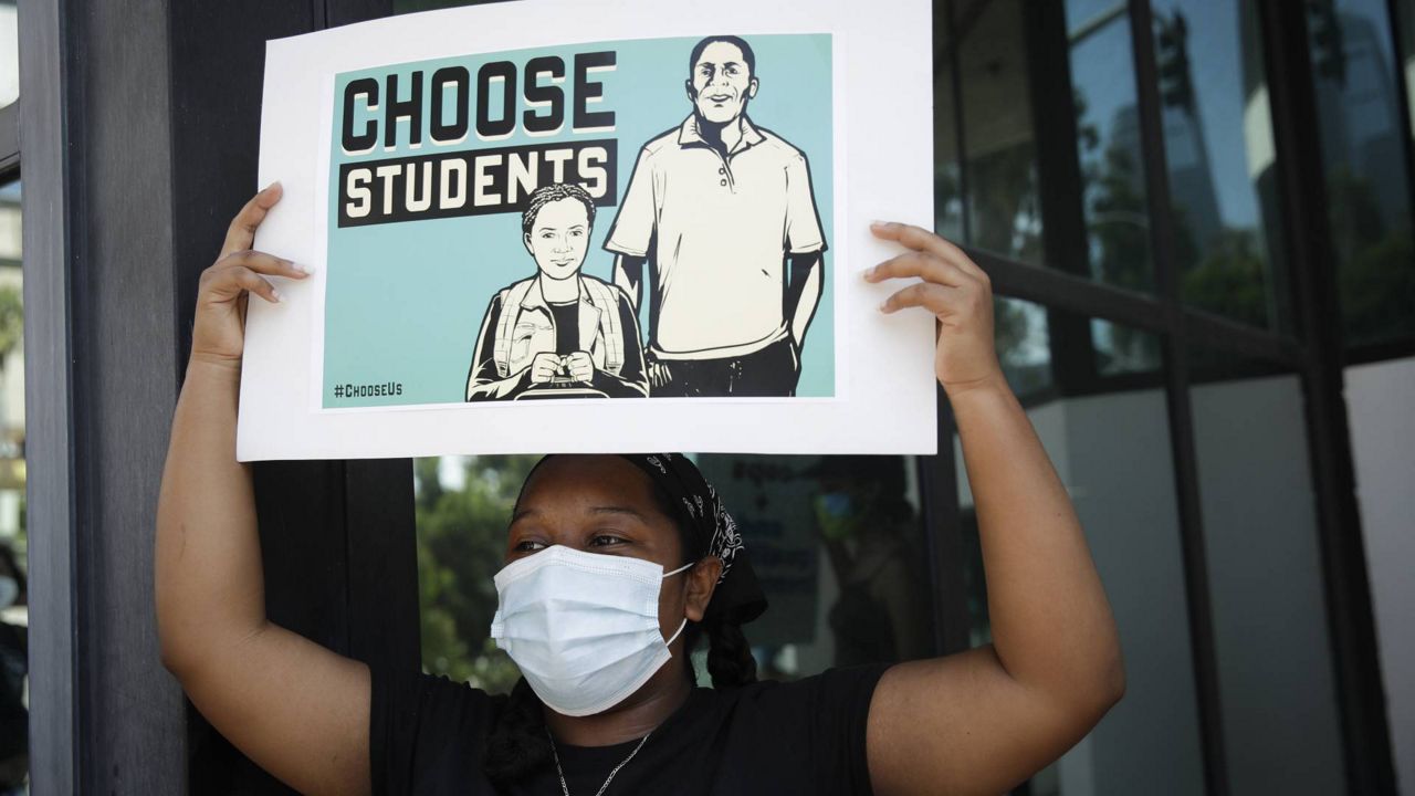 A demonstrator holds a sign Monday, Aug. 3, 2020, in Los Angeles. (AP Photo/Marcio Jose Sanchez)
