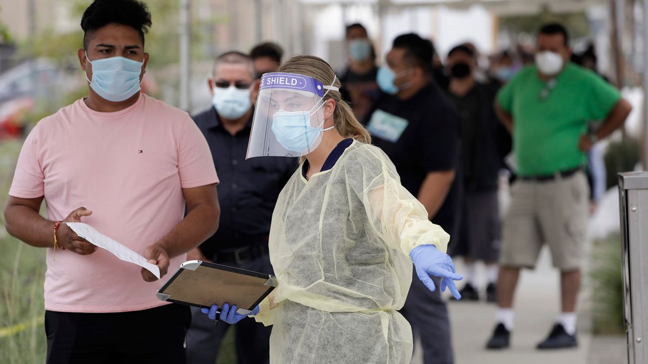 People line up behind a health care worker at a mobile Coronavirus testing site at the Charles Drew University of Medicine and Science in Los Angeles. (AP Photo/Marcio Jose Sanchez, File)