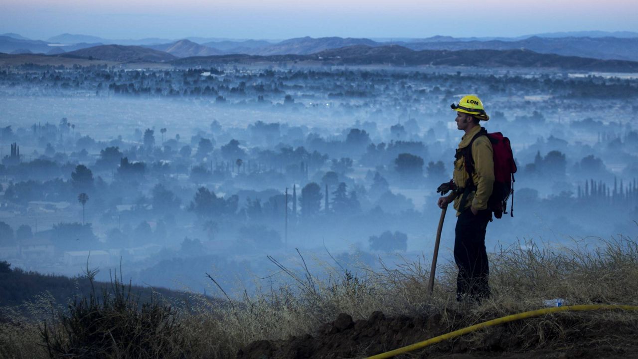 A firefighter watches a brush fire at the Apple Fire in Cherry Valley, Calif., Saturday, Aug. 1, 2020. (AP Photo/Ringo H.W. Chiu)