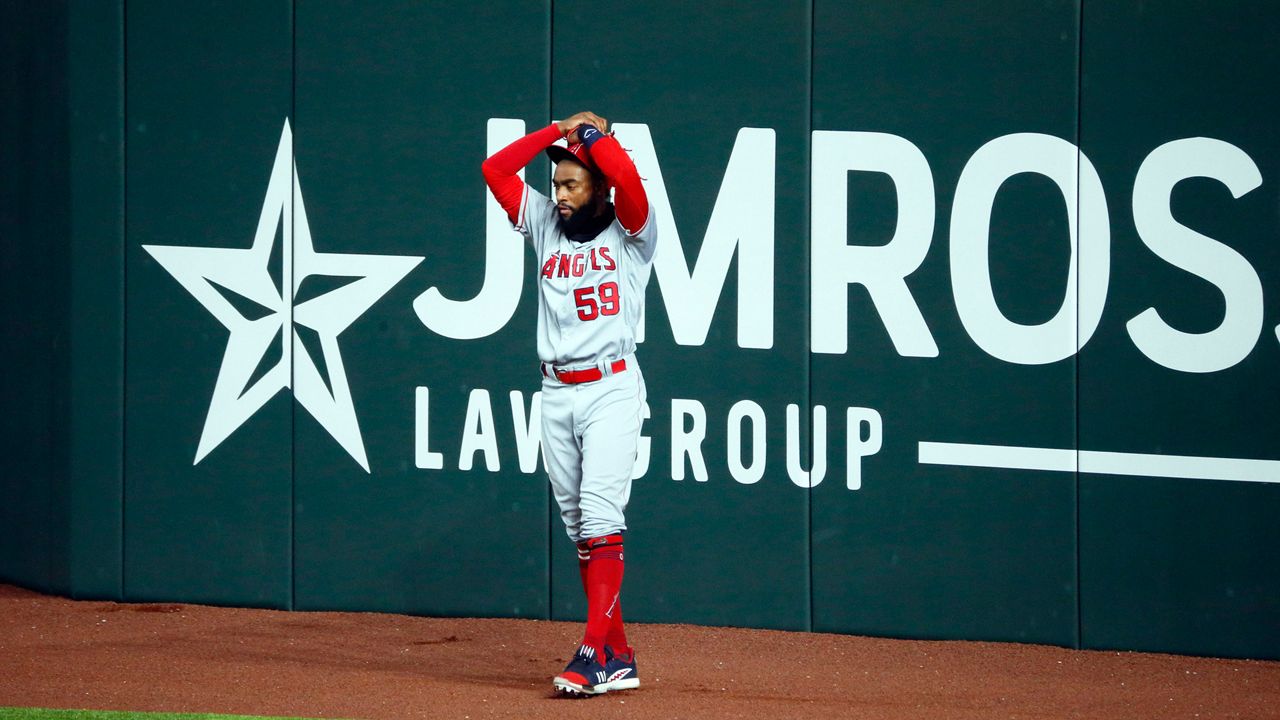 Angels right fielder Jo Adell puts his hands on his head after a fly ball popped out of his glove and over the right field wall during the fifth inning of Sunday's away game against the Rangers.