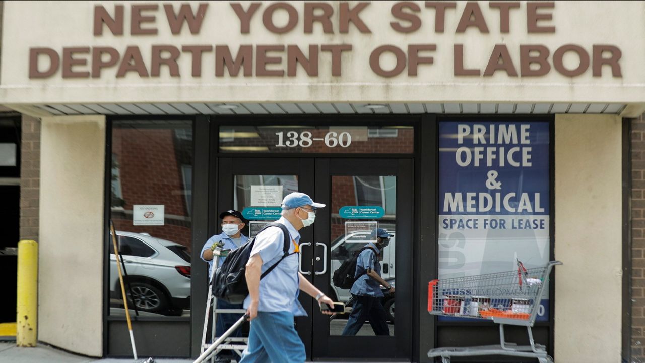  In this June 11, 2020 file photo, pedestrians pass an office location for the New York State Department of Labor in the Queens borough of New York. 