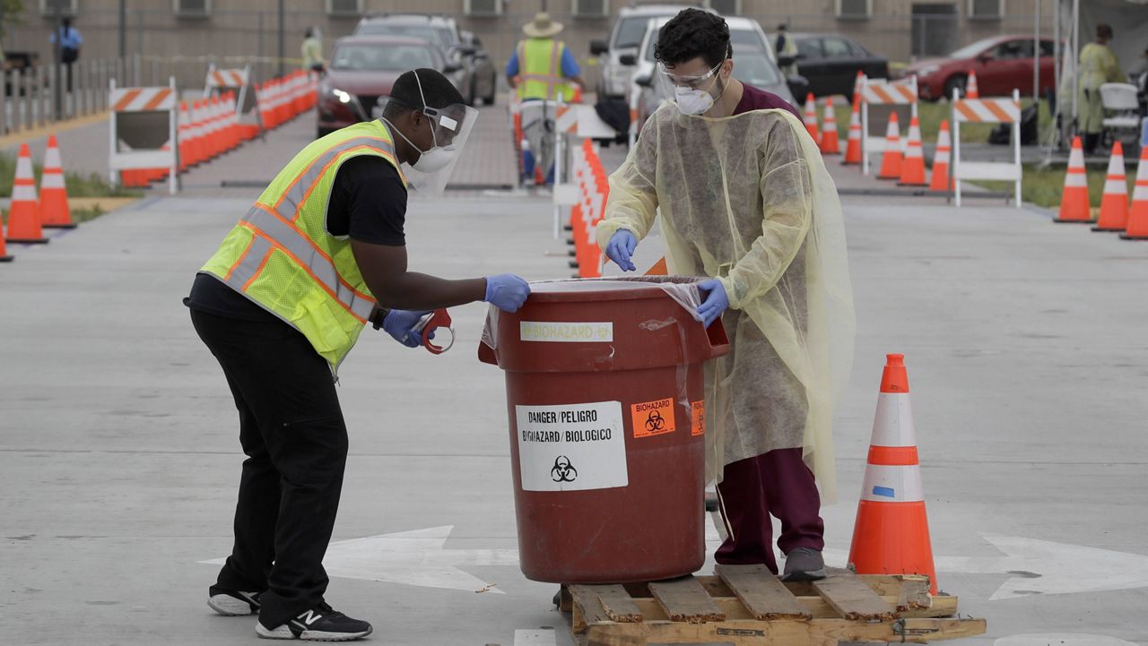 In this July 22, 2020 file photo, workers collect samples at a mobile coronavirus testing site in Los Angeles. (AP Photo/Marcio Jose Sanchez, File)