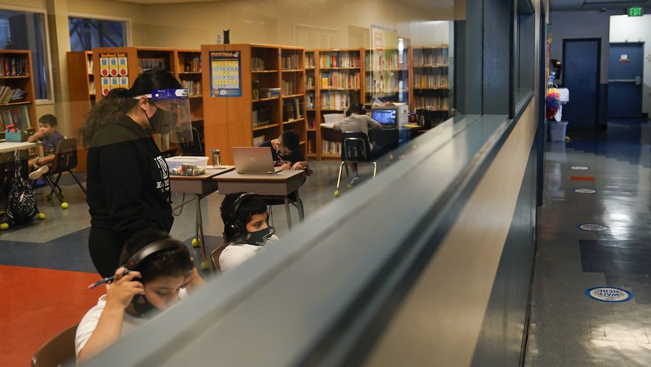 Education Coordinator Madeline Son, left, wear a face shield while helping Los Angeles Unified School District students with their online classes at Boys & Girls Club of Hollywood in Los Angeles, Wednesday, Aug. 26, 2020. (AP Photo/Jae C. Hong)