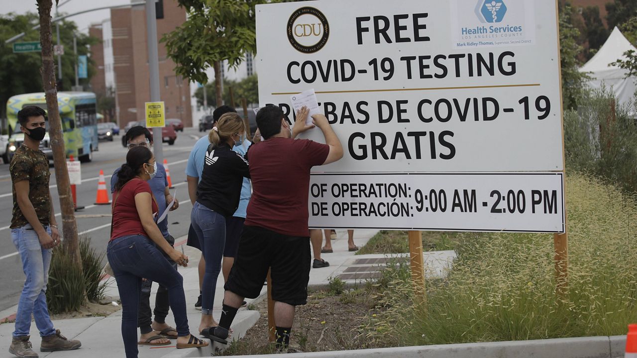 In this July 22, 2020, file photo, people fill out forms at a mobile testing site at the Charles Drew University of Medicine and Science during the coronavirus outbreak in Los Angeles. (AP Photo/Marcio Jose Sanchez, File)
