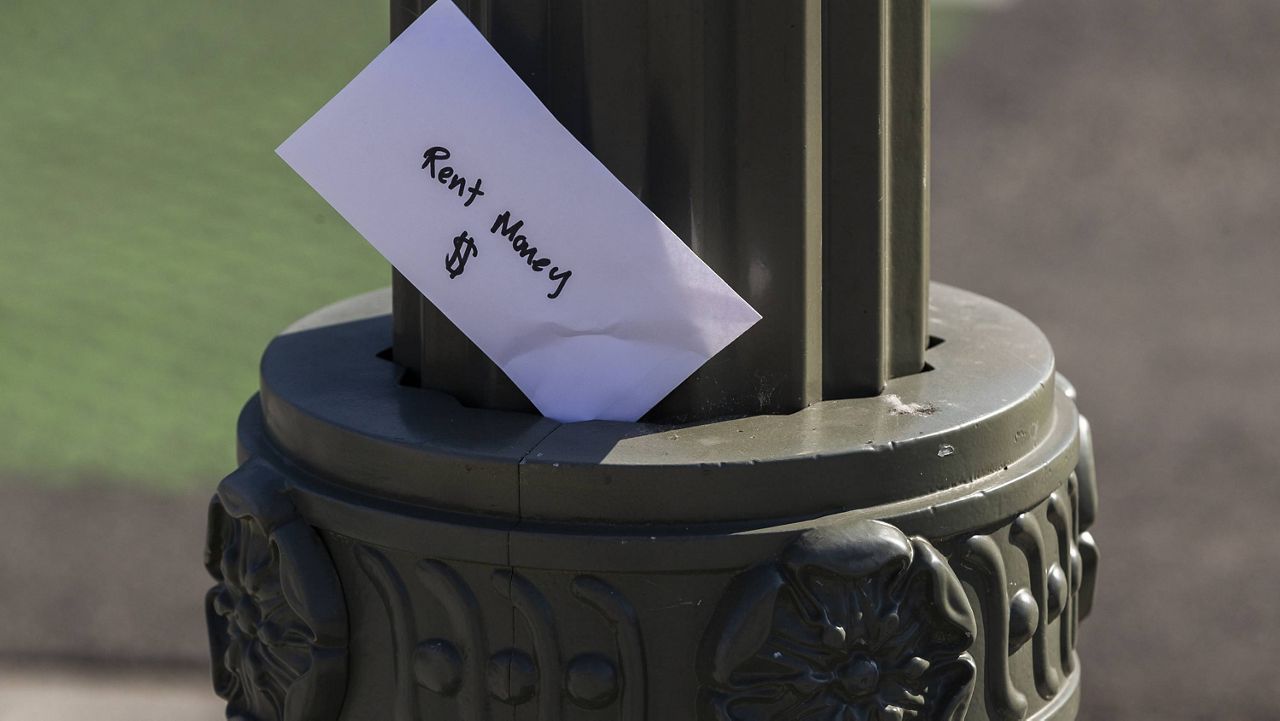 A paper envelope was written with the words "Rent Money $" is left tucked in a lighting pole in the Boyle Heights east district of the city of Los Angeles, Wednesday, April 1, 2020. (AP Photo/Damian Dovarganes, File)