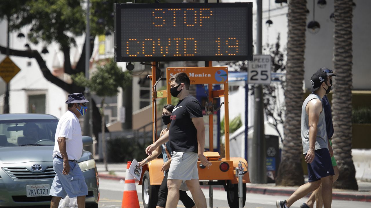 FILE - In this July 12, 2020, file photo, pedestrians wear masks as they cross a street amid the coronavirus pandemic in Santa Monica, Calif. (AP Photo/Marcio Jose Sanchez, File)
