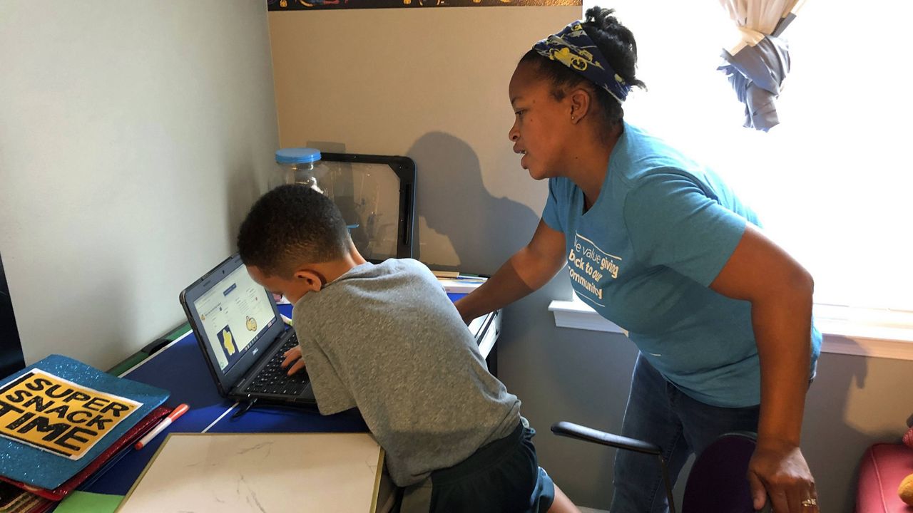 Tiffany Shelton helps her 7-year-old son, P.J. Shelton, a second-grader, during an online class at their home in Norristown, Pa., on Sept. 3, 2020. (AP Photo/Michael Rubinkam)