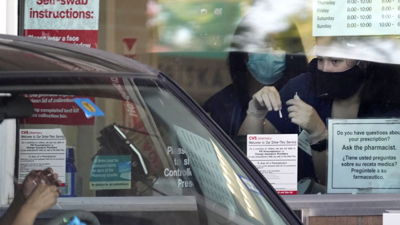 File - Pharmacy workers give instruction on how to administer a self COVID-19 nasal swab test at a drive-up CVS pharmacy in Dallas, Friday, Sept. 18, 2020. (AP Photo/LM Otero)