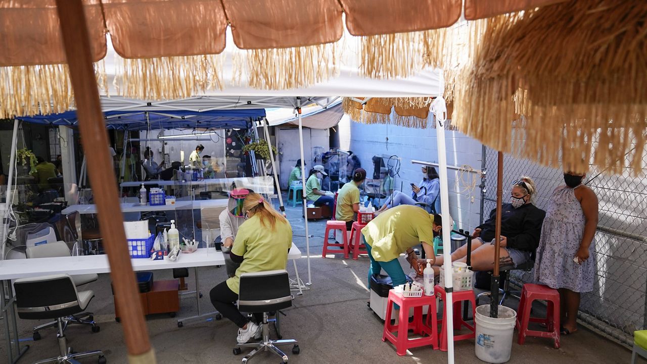 In this July 22, 2020 file photo, customers get their nails done outside Pampered Hands nail salon in Los Angeles. (AP Photo/Ashley Landis, File)