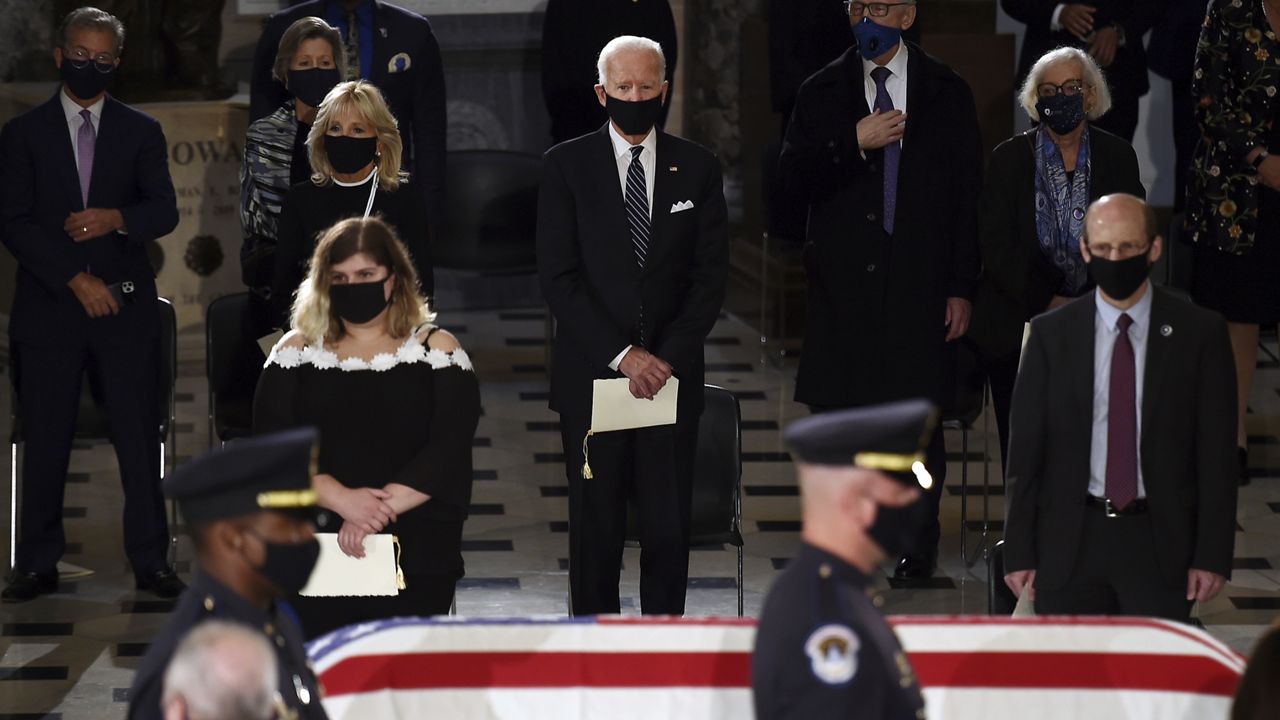 Democratic presidential candidate former Vice President Joe Biden, center, and his wife Jill Biden stand as the flag-draped casket of Justice Ruth Bader Ginsburg lies in state in Statuary Hall of the U.S. Capitol, Friday, Sept. 25, 2020 in Washington. (Olivier Douliery/Pool via AP)