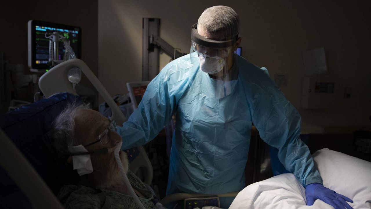 In this July 7, 2020, file photo, Spencer Cushing, 29, tends to David Feinour, a 71-year-old COVID-19 patient, at St. Jude Medical Center in Fullerton, Calif. (AP/Jae C. Hong)