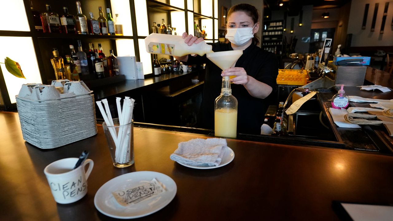 Bartender Devon Schickling prepares lemon juice for drinks, Tuesday, Sept. 29, 2020, at Mama Fox bar and restaurant in the Brooklyn borough of New York. Restaurants in New York can open to indoor dining at 25% of capacity on Wednesday, but they must follow strict protocols.