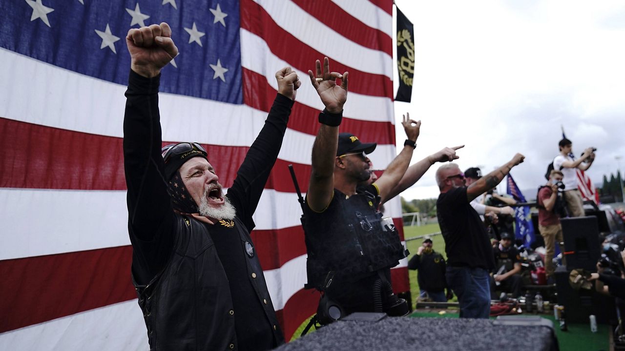 Members of the Proud Boys cheer on stage as they and other right-wing demonstrators rally Saturday in Portland, Oregon. (AP Photo/John Locher)