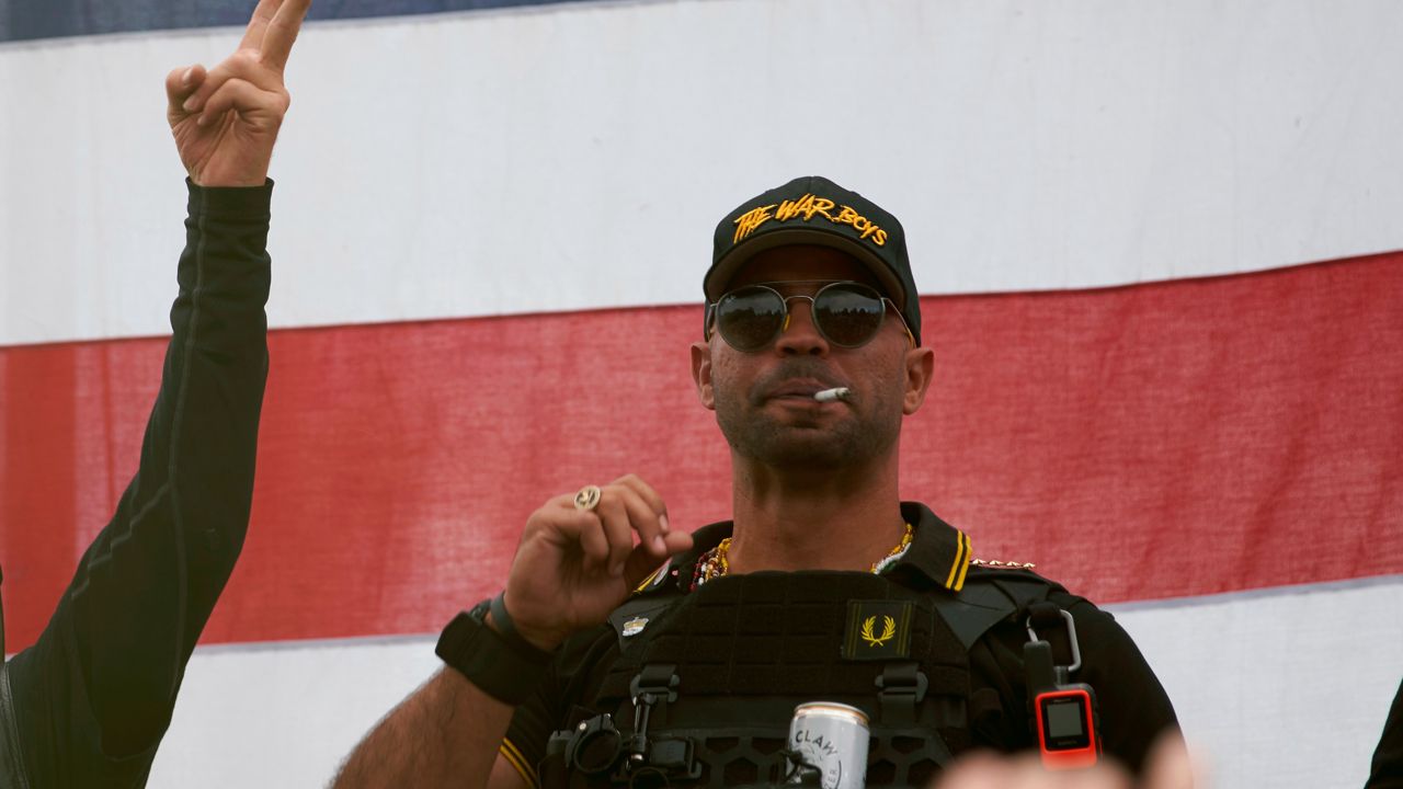 Proud Boys leader Enrique Tarrio wears a hat that says The War Boys and smokes a cigarette at a rally in Delta Park on Saturday, Sept. 26, 2020, in Portland, Ore. (AP Photo/Allison Dinner)