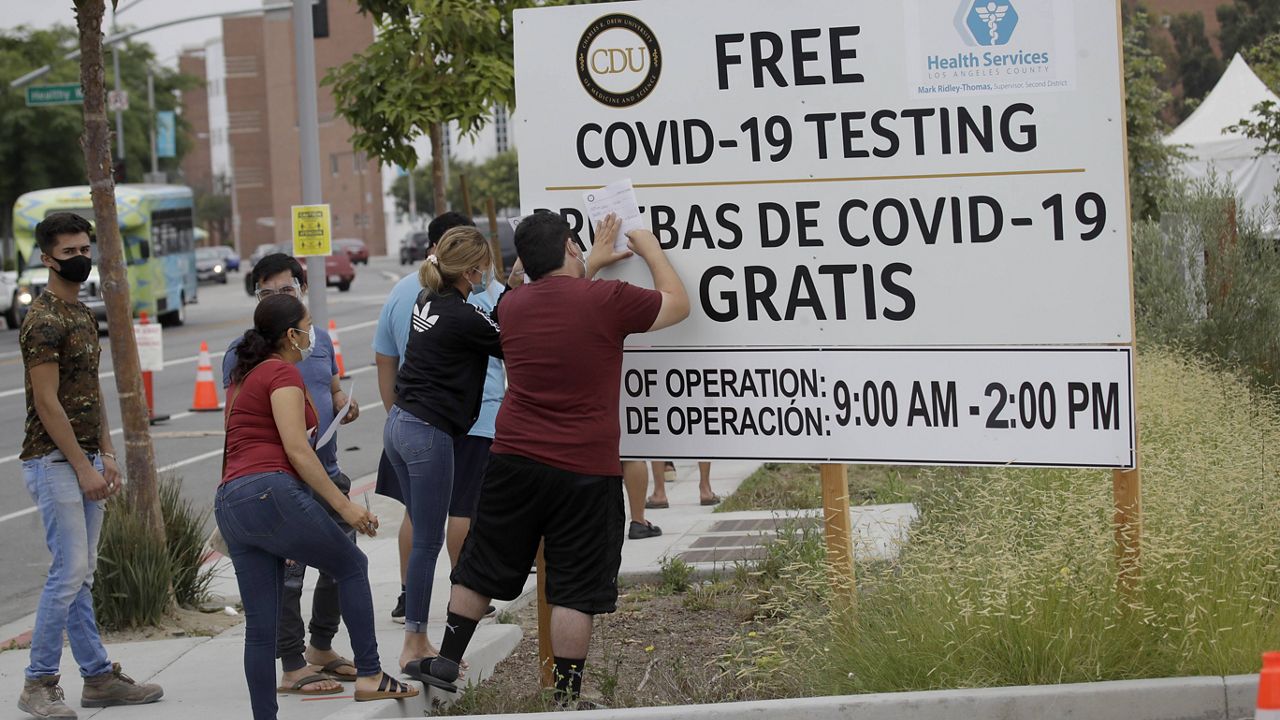 In this July 22, 2020, file photo, people fill out forms at a mobile testing site at the Charles Drew University of Medicine and Science during the coronavirus outbreak in Los Angeles. (AP Photo/Marcio Jose Sanchez, File)