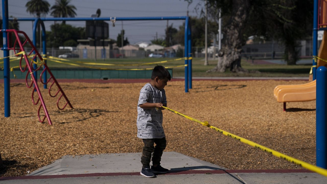 Fernando Olvera, 5, pulls a string of yellow caution tape at a playground closed due to the coronavirus pandemic Thursday, Oct. 1, 2020, in South Central Los Angeles. (AP Photo/Jae C. Hong)