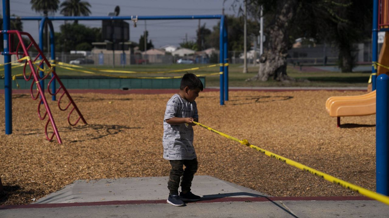 A child pulls a string of yellow caution tape at a playground closed due to the coronavirus pandemic Oct. 1, 2020, in South Central L.A. (AP/Jae C. Hong)