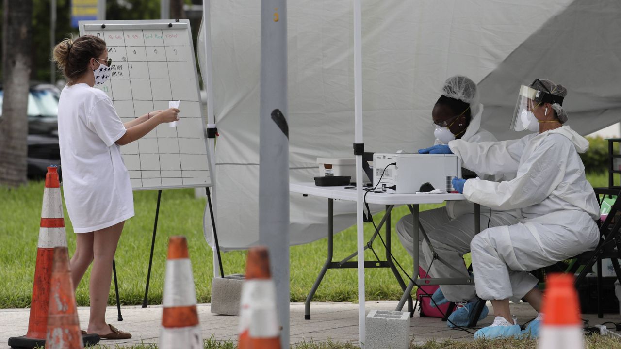 In this Friday, July 17, 2020 file photo, health care workers take information from people in line at a walk-up COVID-19 testing site during the coronavirus pandemic in Miami Beach, Fla. (AP Photo/Lynne Sladky)