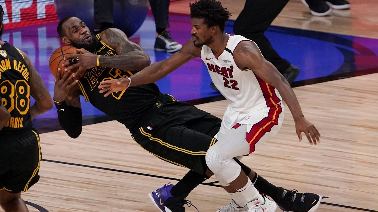 Los Angeles Lakers forward LeBron James pulls rebound away from Miami Heat forward Jimmy Butler during the second half in Game 5 of basketball's NBA Finals Friday, Oct. 9, 2020, in Lake Buena Vista, Fla. (AP Photo/Mark J. Terrill)