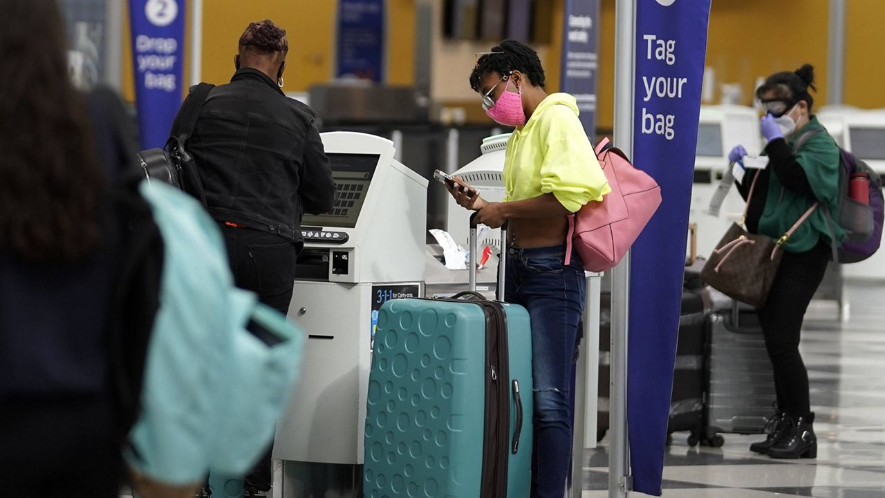 In this Oct. 14, 2020, file photo, travelers check in at the United Airlines self-ticket counter at O'Hare International Airport in Chicago. (AP Photo/Nam Y. Huh)