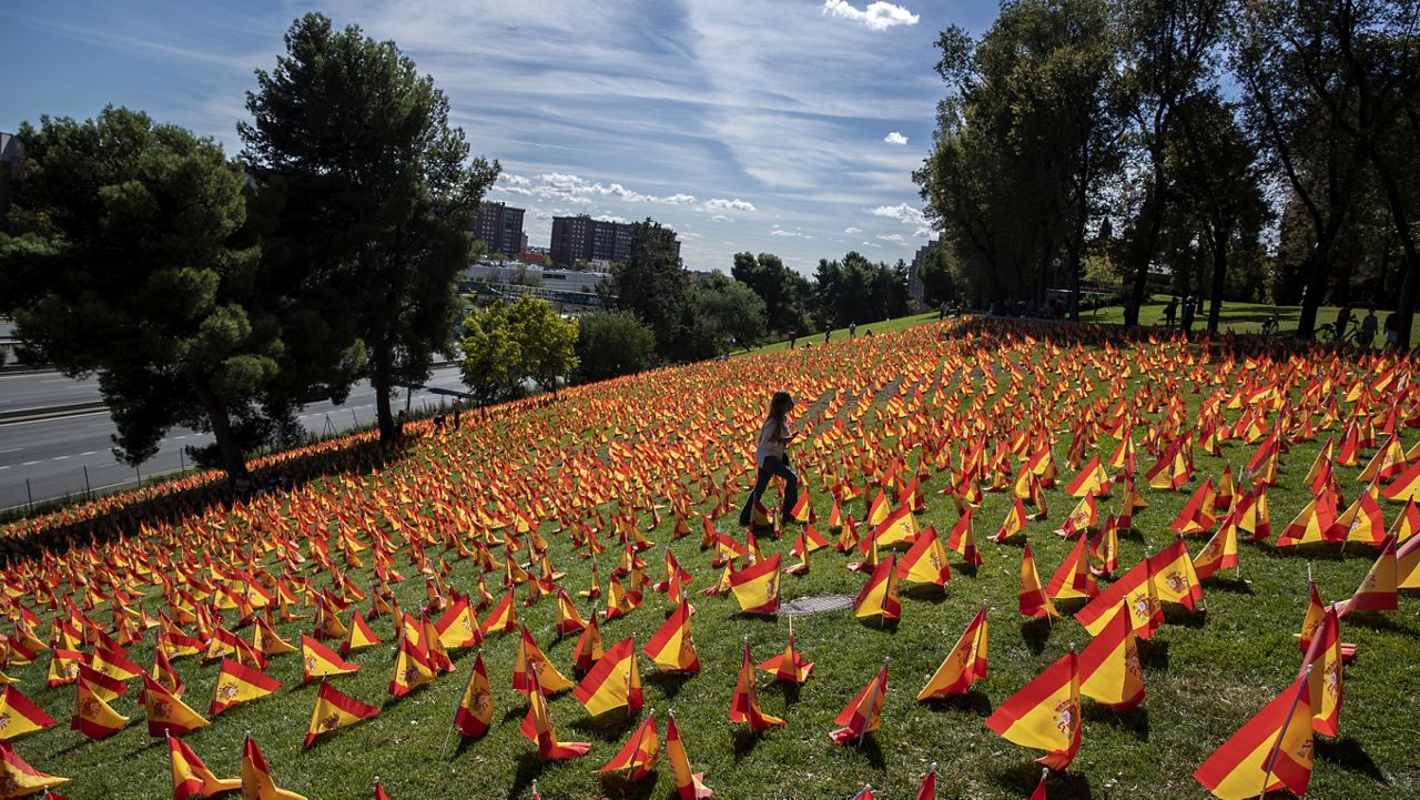 A woman walks among the Spanish flags placed in memory of coronavirus (COVID-19) victims in Madrid, Spain, Sunday, Sept. 27, 2020. (AP Photo/Manu Fernandez)