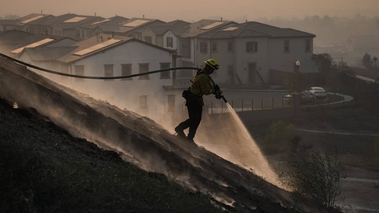 Firefighter Tylor Gilbert puts out hotspots while battling the Silverado Fire, Monday, Oct. 26, 2020, in Irvine, Calif. (AP Photo/Jae C. Hong)