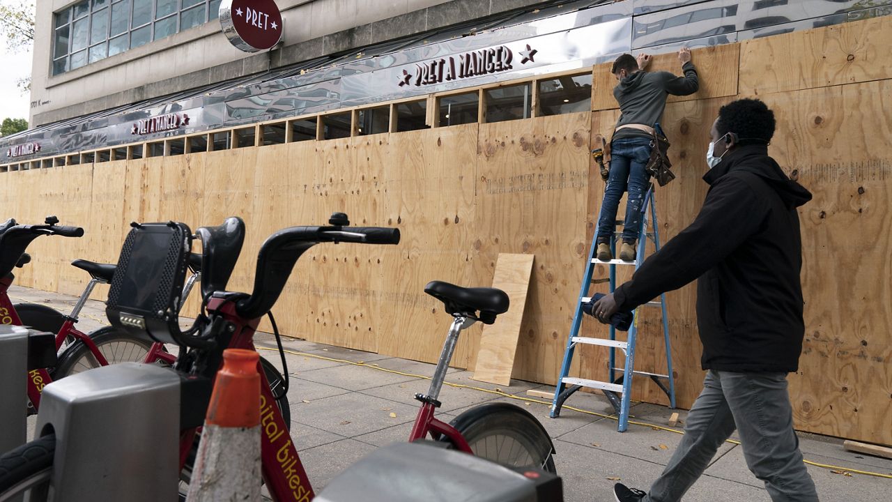A pedestrian passes work being done to board up a Pret A Manger restaurant along K Street, Friday, Oct. 30, 2020, ahead of the presidential election, in downtown Washington not far from the White House. (AP Photo/Jacquelyn Martin)
