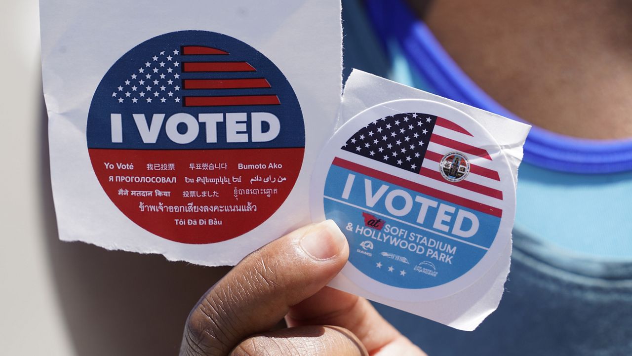 "I voted" stickers for the SoFi Stadium & Hollywood Park voting location are displayed by a voter in Inglewood, Calif., Friday, Oct. 30, 2020. (AP Photo/Damian Dovarganes)