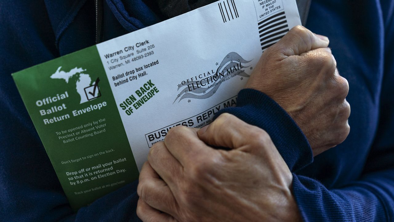 Diane Spiteri clutches her absentee ballot before dropping it off at the city clerk's office in Warren, Mich., Wed, Oct. 28, 2020. "I just can't wait until the whole thing is over. And I think it's long from over, even after Tuesday. There's just so much anxiety," said Spiteri. (AP Photo/David Goldman)