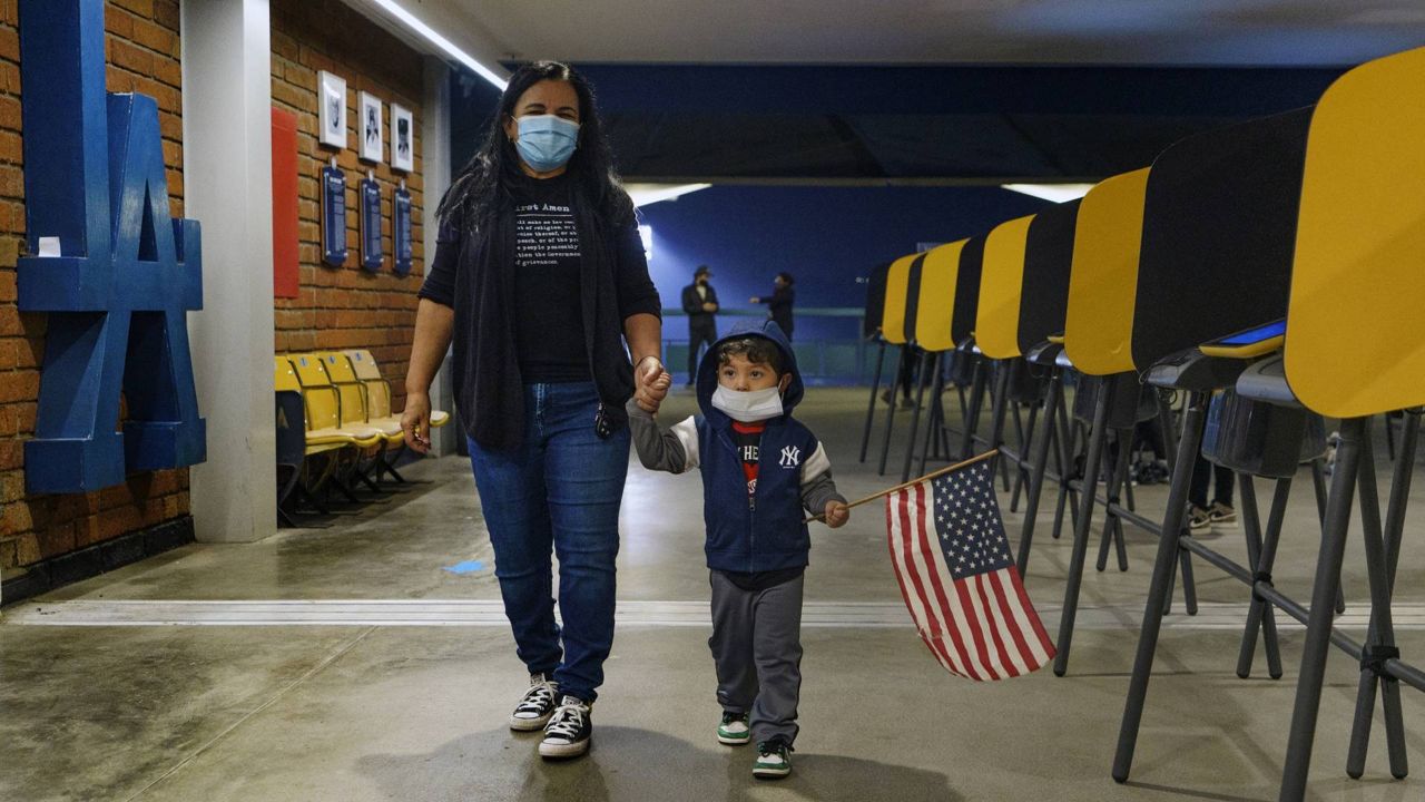 A former L.A. Unified School history teacher holds the hand of her grandson after casting her ballot in-person at the Top of the Park at Dodger Stadium, Monday, Nov. 2, 2020. (AP/Damian Dovarganes)